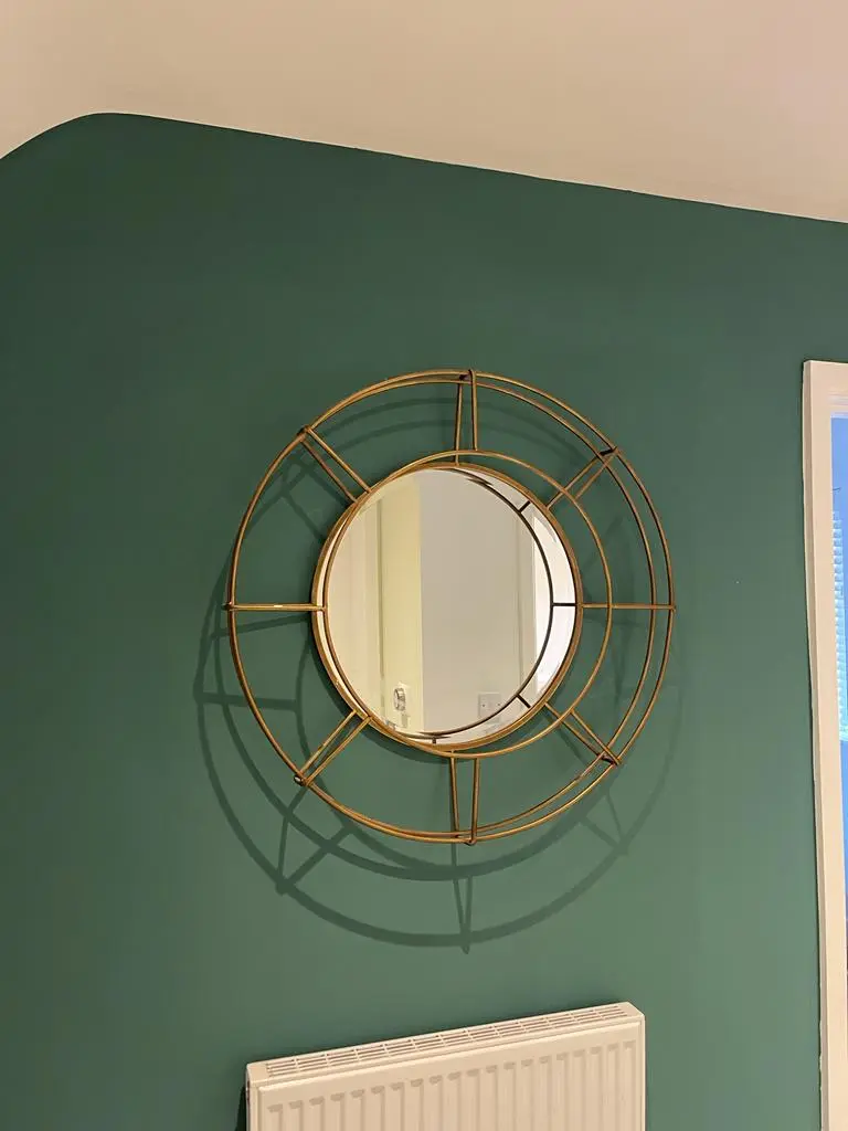 Freshly painted room with green walls and a mirror.