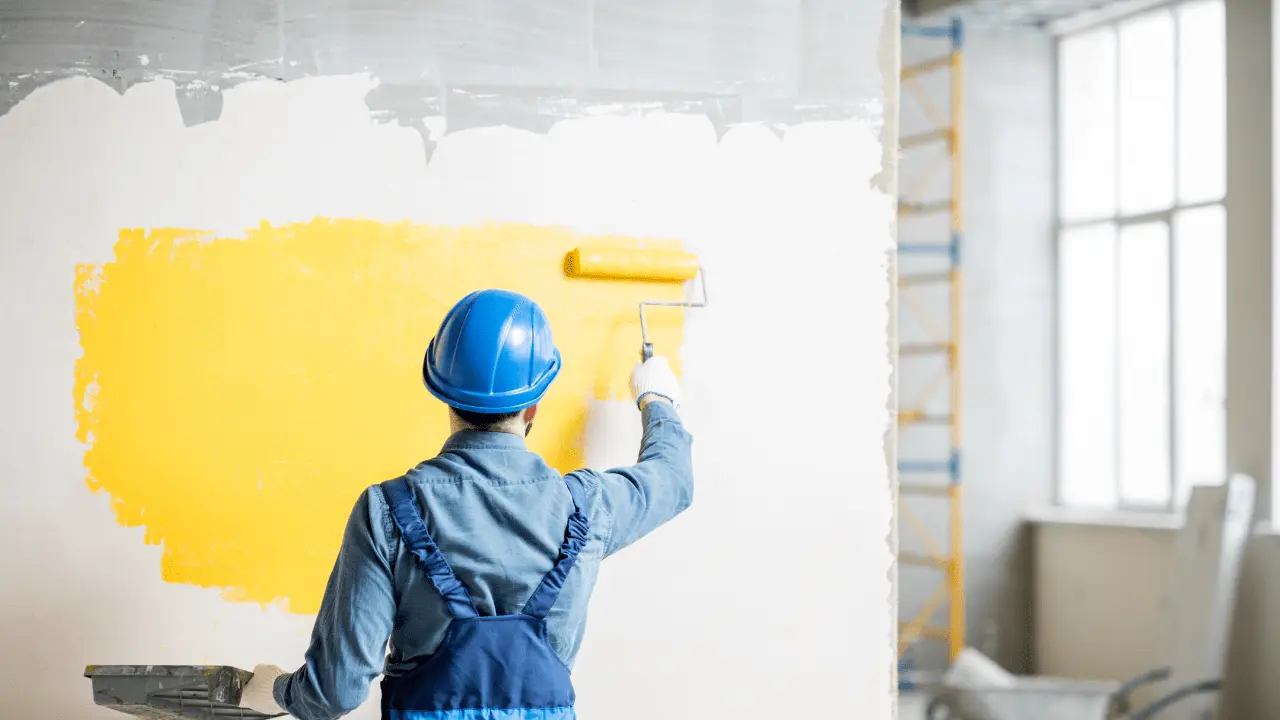 Painting the wall with yellow paint.
